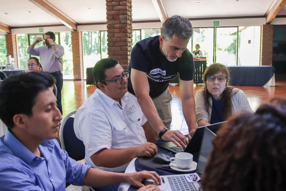 Julián Martínez, from Suricata Labs, works with a group of advisors at a computer during a hands-on session of the program in El Salvador