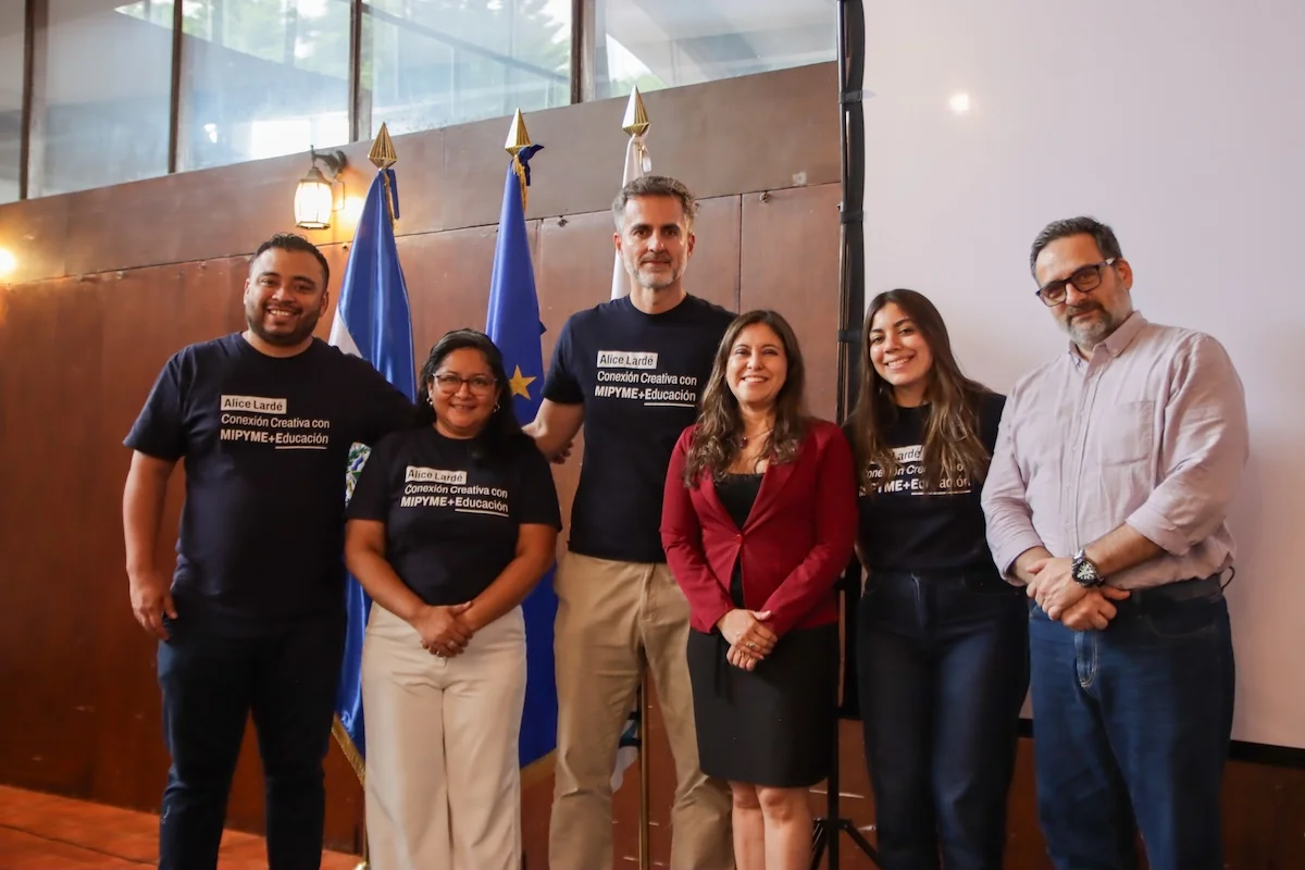 The Alice Lardé, Creative Connection with MSMEs and Education program team, together with OEI representatives in El Salvador, in front of the flags of El Salvador and the European Union